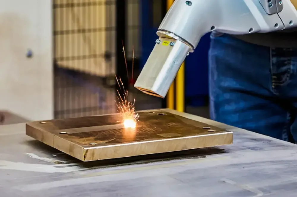 Robotic laser cleaning system removing contamination from a metal surface with sparks